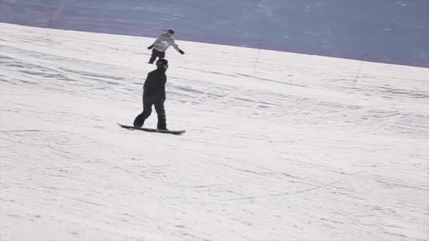 Sochi, Rusko - 1. dubna 2016: Snowboardista jízda ve svahu, skočit z můstku. Lyžařské středisko. Zvedněte ruce. Slunečno — Stock video