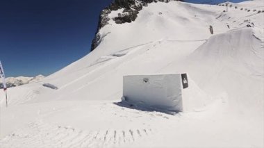 Sochi, Rusya Federasyonu - 1 Nisan 2016: Sıçrama tahtası, Snowboarder atlamak bacakları havada şişiriyor. Karlı dağlar. Mavi gökyüzü. Güneşli gün
