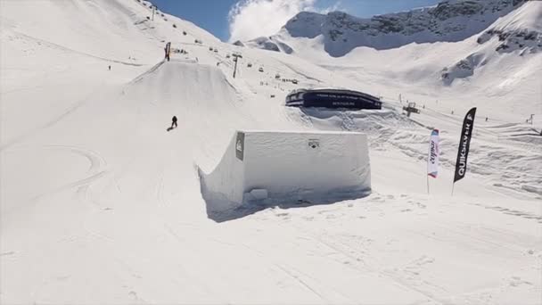 Sochi, Ryssland - April 1, 2016: Skidåkare hoppa från springboard gör full flip i luften. Landskap med snötäckta berg. Blå himmel. Kameramannen — Stockvideo