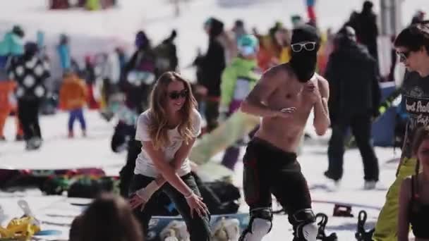 SOCHI, RÚSSIA - 2 de abril de 2016: Menina de óculos de sol e homem de máscara dançam no acampamento entre as pessoas. Estância de esqui . — Vídeo de Stock