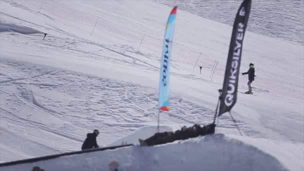 Sotschi, Russland - 2. April 2016: Snowboarder springen vom Sprungbrett, schnappen sich Snowboard auf Skigebiet. Sonnig. Reiten — Stockvideo