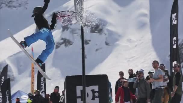 SOCHI, RUSSIE - 1er AVRIL 2016 : Le snowboarder saute sur le tremplin pour lancer une boule de neige dans le panier de basket. Les gens . — Video