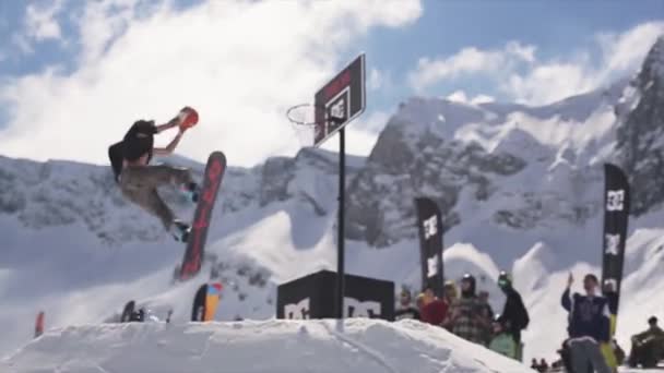 SOCHI, RUSIA - 1 DE ABRIL DE 2016: Paseo de snowboarder en una pelota de lanzamiento de trampolín en una canasta de baloncesto. Público. Deporte — Vídeo de stock