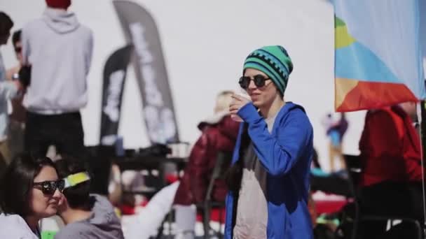 ソチ, ロシア連邦 - 2016 年 4 月 1 日: 女の子帽子サングラス飲むコーヒー。スキー リゾート。エンカンプします。晴れた日。くつろぎを得る人 — ストック動画