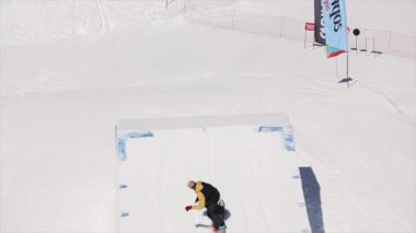 Soçi, Rusya - 1 Nisan 2016: Snowboarder atlamak sıçrama tahtası olun havada tam fiske vurmak. Karlı dağlar. Güneşli bir gün. Kayak Merkezi