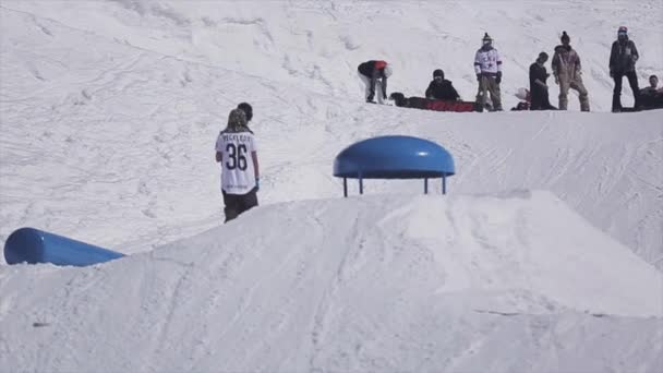 SOCHI, RUSIA - 2 DE ABRIL DE 2016: Salto snowboarder desde trampolín, hacer voltereta. Estación de esquí. Soleado. Deporte activo — Vídeos de Stock