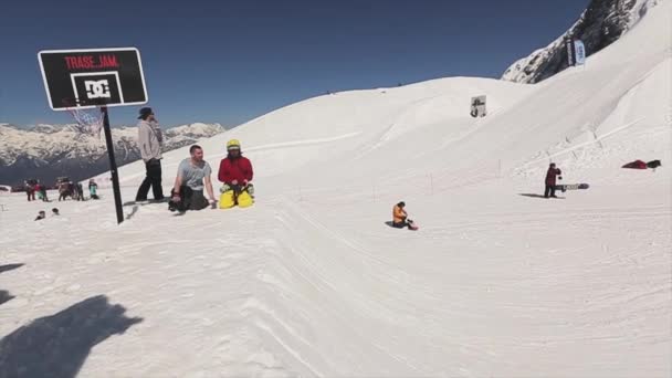 SOCHI, RUSIA - 1 DE ABRIL DE 2016: Snowboarder saltar en el trampolín tratar de lanzar la pelota en la canasta de baloncesto. Gente — Vídeos de Stock