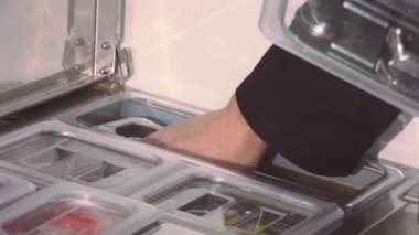 Aşçı ile midye tava, masada yeşil plastik konteyner üzerinden fesleğen ekleyin. Diğer tava kapağı.