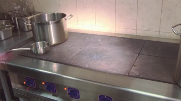 Cook in uniform wiping working stove on kitchen of restaurant by rag. Aluminum pans. Cooking — Stock Video