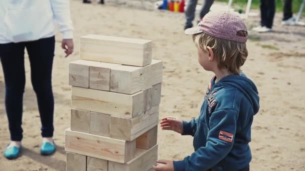 Petersburg, Rosja - 6 września 2014: Little boy Zagraj w grę jenga duże na piasku. Dziewczyna mu pomóc. Letni festiwal. Ludzie — Wideo stockowe