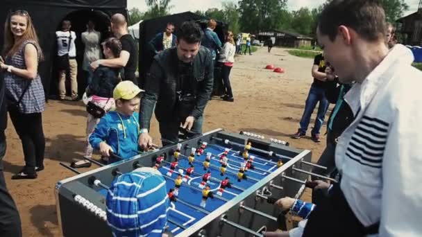 SAINT PETERSBURG, RUSSIA - SEPTEMBER 6, 2014: Little boys in cap play american table soccer with adult. Sand. Summer festival — Stock Video