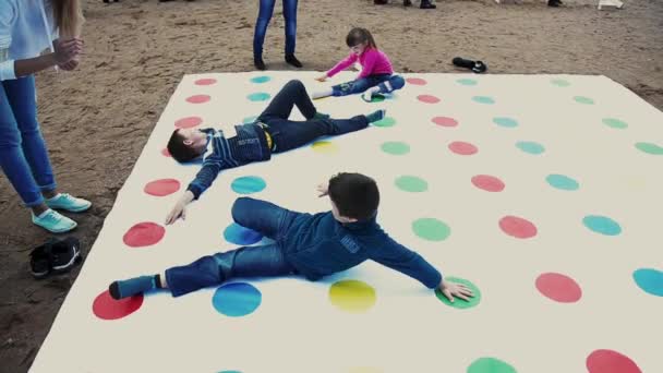 Sint-Petersburg, Rusland - 6 September 2014: Twee jongens en meisje spelen populaire twister spel op zand. Zomerfestival. Zonnige dag. — Stockvideo