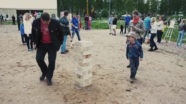 SAN PETERSBURG, RUSIA - 6 DE SEPTIEMBRE DE 2014: Un niño pequeño juega un gran juego de jenga con un hombre adulto en la arena. Festival de verano. Gente — Vídeos de Stock