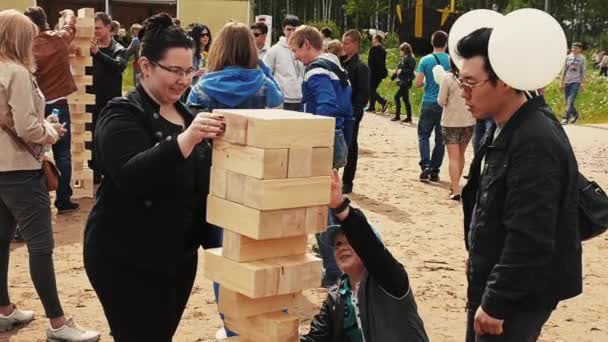 SAN PETERSBURG, RUSIA - 6 DE SEPTIEMBRE DE 2014: Un niño pequeño juega un gran juego de jenga con un hombre adulto, una mujer en la arena. Festival. Familia — Vídeo de stock