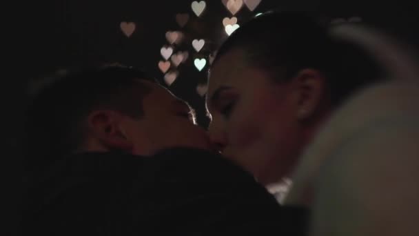 Rückseite des küssenden Hochzeitspaares. Feuerwerk explodiert in Form bunter Herzen am Nachthimmel — Stockvideo