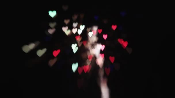 La parte trasera de la pareja de boda mira los fuegos artificiales en el cielo en forma de corazones coloridos. Felicidad — Vídeos de Stock