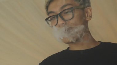 Gözlüklü Asyalı çocuk nefes elektronik sigara buhar. Vaper. Sigara içen.