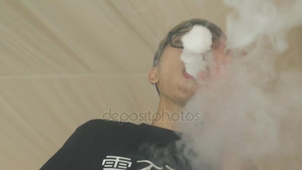 Aziatische jongen in glazen maken wolken van elektronische sigaret stoom. Vaper. Roken — Stockvideo