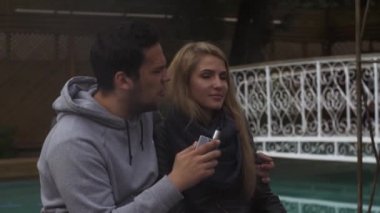Çift yüzme havuzunda Caddesi üzerinde oturmak. Adam duman elektronik sigara. Vaper