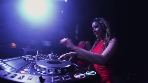 Petrohrad, Rusko - 30. června 2016: Mc dívka v Zaječí masku a dj dívka v červených šatech mix na točnu v nočním klubu. — Stock video