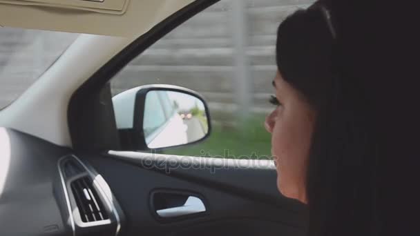 Άποψη του νεαρή μελαχρινή κοπέλα κάθεται μέσα οδήγηση αυτοκινήτου στο κάθισμα του συνοδηγού. Ηλιόλουστη μέρα του καλοκαιριού. Ταξίδια — Αρχείο Βίντεο
