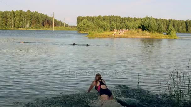 在阳光明媚的夏日在绿色森林湖中游泳的人。自然。在泳装跑到水中的女孩 — 图库视频影像