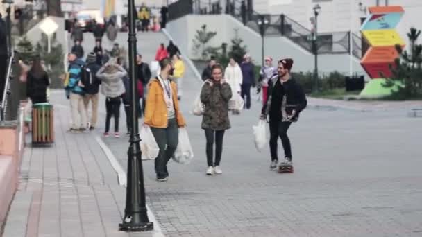 Soçi, Rusya - 27 Mart 2016: Üç arkadaş yürüyüş büyük beyaz paketleri ile sokakta görünümünü. İnsanlar. Binalar. Şehirde akşam. — Stok video