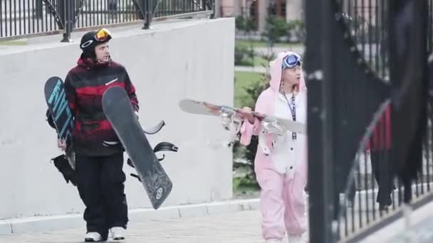 Sochi, Російська Федерація - 27 березня 2016: Вигляд дівчина сноубордист ходьби, на вулиці в рожевий заєць костюм з людиною в погонах. Люди. Вечір — стокове відео