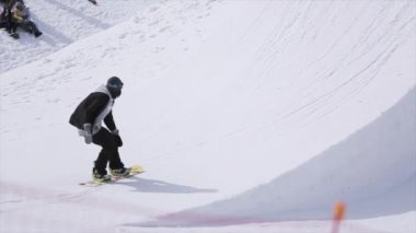 Sochi, Rusya - 1 Nisan 2016: Sıçrama tahtası havada dönerek, Snowboarder atlamak. İnsanlar yamaçta rahatla. Güneşli