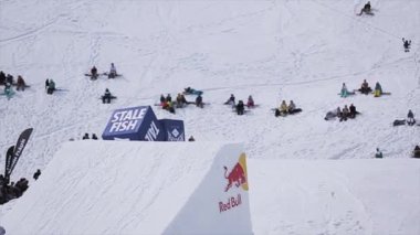 Soçi, Rusya - 1 Nisan 2016: Snowboarder atlamak sıçrama tahtası. Peyzaj dağlar. İnsanlar yamaçta oturmak