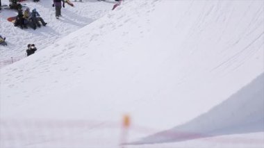Sochi, Rusya Federasyonu - 1 Nisan 2016: Snowboarder sıçrama sıçrama tahtası yapmak üzerinden çevirir, ayak şişiriyor. İnsanlar yamaçta sakin ol.