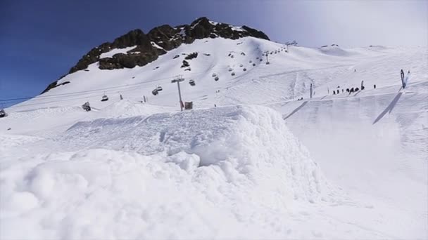 Σότσι, Ρωσία - 1η Απριλίου 2016: Snowboarder άλμα από την αφετηρία μπροστά κάμερα. Χιονισμένα βουνά. Μπλε του ουρανού — Αρχείο Βίντεο