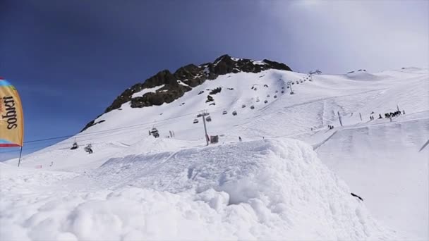 Soczi, Rosja - 1 kwietnia 2016: Snowboardzista skakać z springboard, grab pokładzie w powietrzu z przodu kamery. Krajobraz. — Wideo stockowe