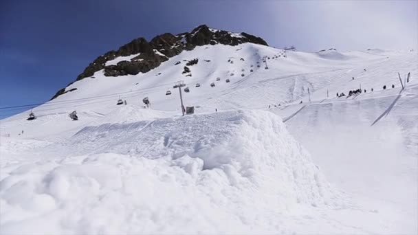 SOCHI, RUSSIA - 1 de abril de 2016: Snowboarder jump from springboard, make stunt in front câmera. Paisagem. Ensolarado — Vídeo de Stock