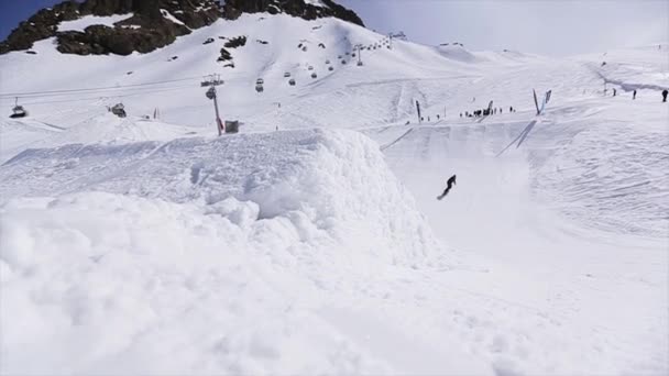 Soczi, Rosja - 1 kwietnia 2016: Snowboardzista skok na trampolinę, zrobić klapki z przodu kamery. Krajobraz. Słoneczny dzień — Wideo stockowe