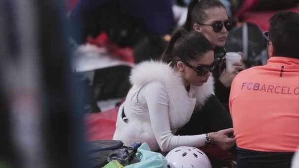 SOCHI, RUSSIA - APRIL 1, 2016: People relax in encamp on ski resort. Girl in sunglasses drink coffee. Crowds. — Stock Video