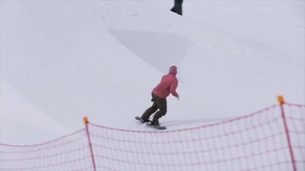 Sochi, Rusko - 1. dubna 2016: Snowboardista skok z odrazový můstek, drapákem snowboard ve vzduchu. Kameraman. Hory — Stock video