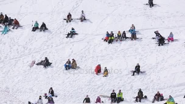 SOCHI, RUSIA - 1 DE ABRIL DE 2016: Multitud de personas se relajan en la ladera nevada. Estación de esquí. Día soleado. Snowboarders. Esquiador — Vídeos de Stock