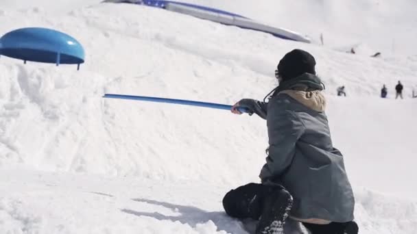 ソチ, ロシア連邦 - 2016 年 4 月 3 日: スキー リゾート。トレーナーは、スノーボーダーのためのばね板として青いステーブを保持します。晴れた日. — ストック動画