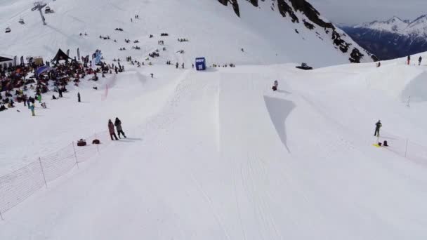 Sochi, Rusko - duben 4, 2016: Quadrocopter natáčení snowboardista skok z odrazový můstek. Sledovat lidi na svahu. — Stock video