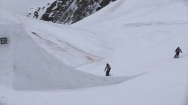 Soçi, Rusya - 4 Nisan 2016: Kayakçı olun yüksek atlama üzerinden sıçrama tahtası. Kayak Merkezi. Gri hava. Karlı dağlar