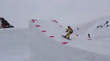Sochi, Rusya Federasyonu - 4 Nisan 2016: Yüksek sıçrama tahtası, Sarı takım elbise atlamak snowboard yapmak aşırı flip havada.