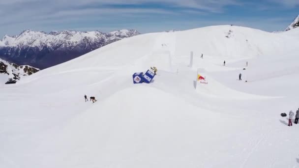 Sochi, Rusland - 4 April 2016: Quadrocopter schieten snowboarder rijden op ski-oord. Landschap van bergen. — Stockvideo