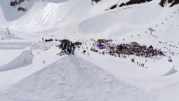 Sochi, Ryssland - April 4, 2016: Quadrocopter skjuta snowboardåkare rida på språngbräda. Skidorten. Skaror av människor — Stockvideo