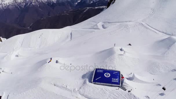 Sochi, Rusland - 4 April 2016: Quadrocopter schieten enorme blauwe training trampoline op ski-oord. Bergen. Sneeuw — Stockvideo