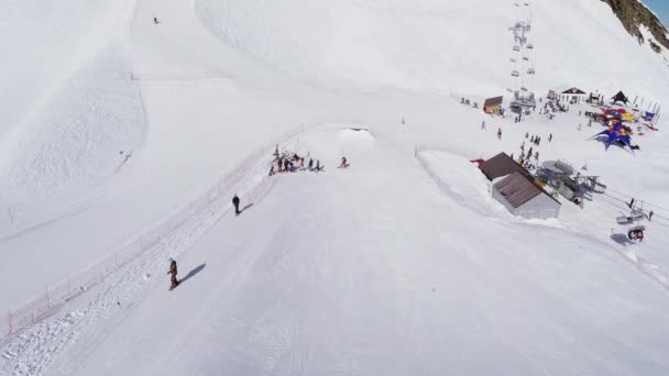 Sotschi, Russland - 4. April 2016: Quadrocopter fliegen über Sprungbretter im Skigebiet. Snowboarder fahren. sonniger Tag — Stockvideo