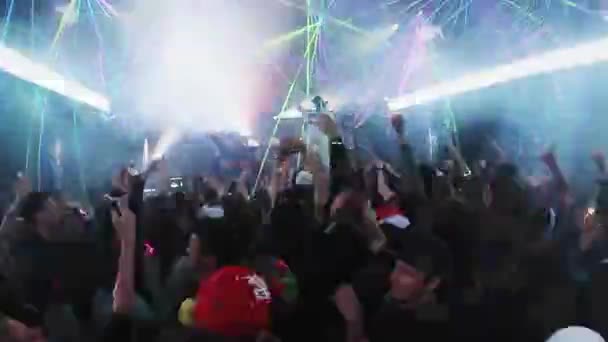 SOCHI, RUSSIA - APRIL 4, 2016: People raise hands jump in nightclub. Mc man on stage. Laser show. Illuminations — Stock Video