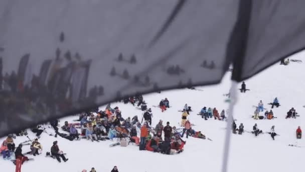 Sotschi, Russland - 4. April 2016: Snowboarder und Skifahrer entspannen im Camp. Skigebiet. schwarze Fahne schwenkend. — Stockvideo