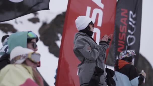 SOCHI, RUSSIA - 4 APRILE 2016: La ragazza con gli occhiali da sole applaude all'accampamento tra le altre persone. Località sciistica. Sventola bandiera — Video Stock