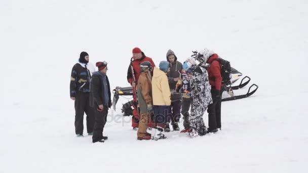 Sochi, Rusland - 4 April 2016: Groep snowboarders help gewond rider opstaan op de sneeuwscooter. Skigebied. — Stockvideo